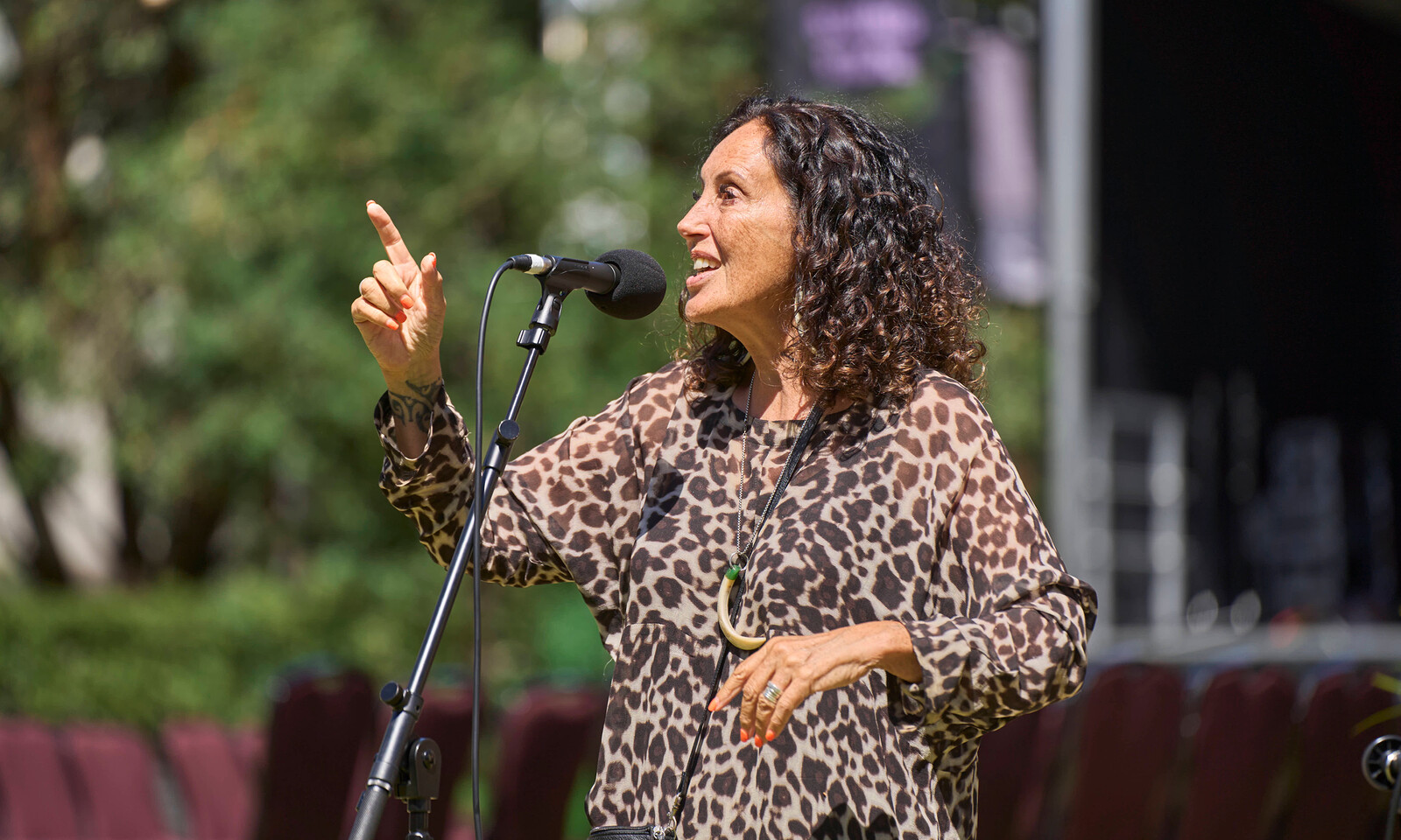 A speaker addresses a crowd outdoors while standing at a microphone.